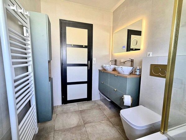 Casa de banho com sanita, lavatório com espelho e radiador.