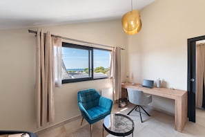 Ein modernes Zimmer mit Schreibtisch, Stuhl und Meerblick.