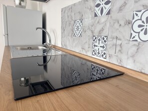 A modern kitchen with a sleek black countertop, a stainless steel sink, and a wooden backsplash. - The Terrace (Villa San Leonardo)