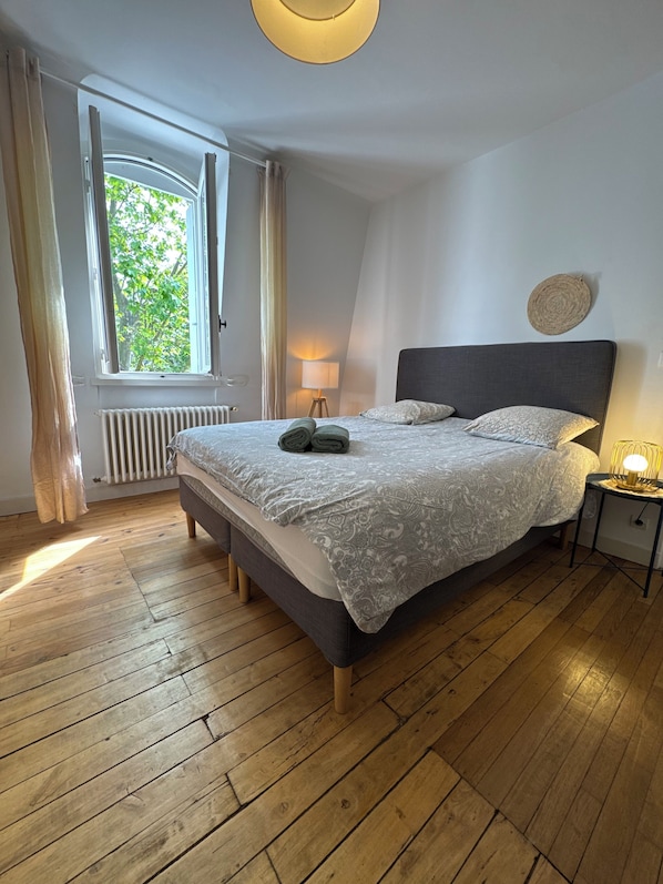A bedroom with a bed, a window, a lamp, and a radiator.