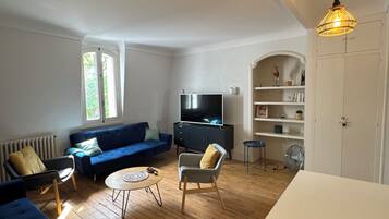 A living room with a blue sofa, a TV, a small table, and a white cabinet.
