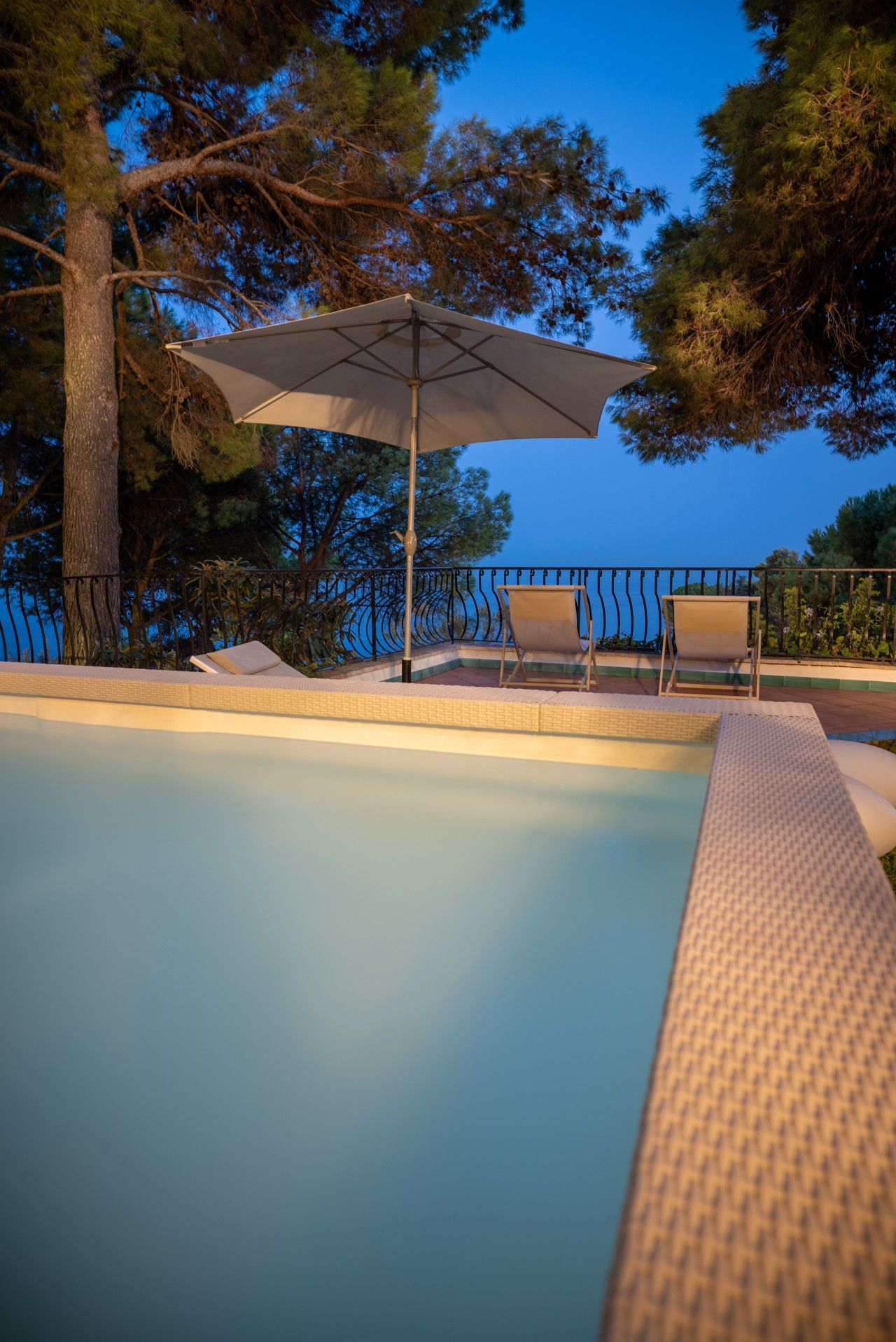 Une piscine avec un transat et un parasol.
