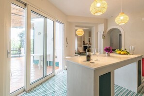 Una cucina moderna con un'isola centrale, ampie finestre e vista sul patio esterno.