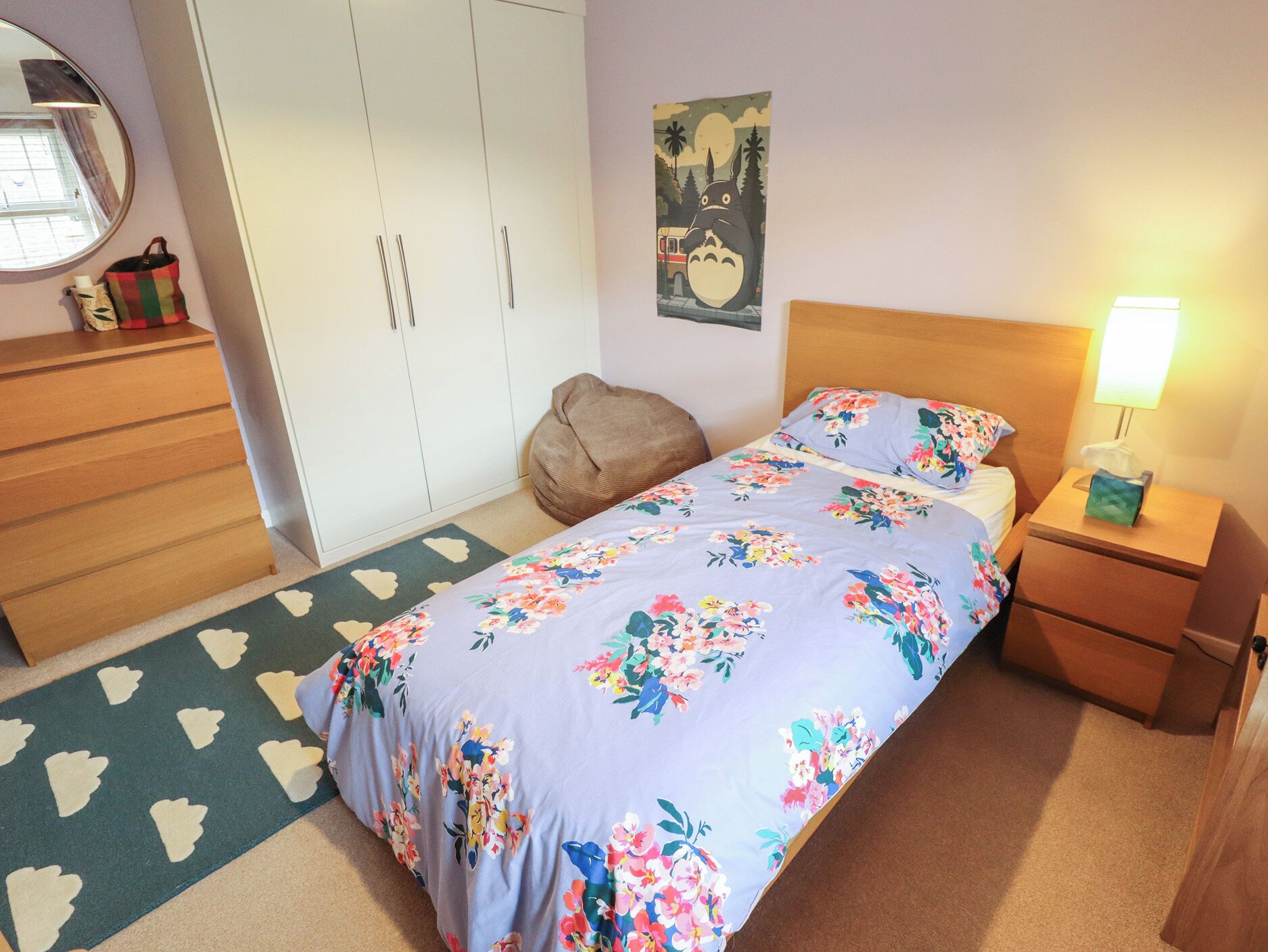 Una camera da letto con un letto, un comodino, una cassettiera, uno specchio e un quadro appeso al muro.