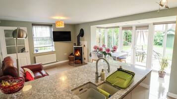 A modern kitchen with a built-in stove, a large window, and a dining area with outdoor seating.