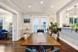 A dining area with a wooden table, chairs, and a view of the outdoors through large windows. - The 23rd Ave Home (Seattle)