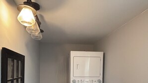 A laundry room with a washing machine, a light fixture, and a door. - 3-bedroom house in charming Clarksville with AC for relaxing stays (Clarksville)