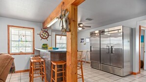 A kitchen with a bar stool area, stainless steel appliances, and a wooden beam structure.