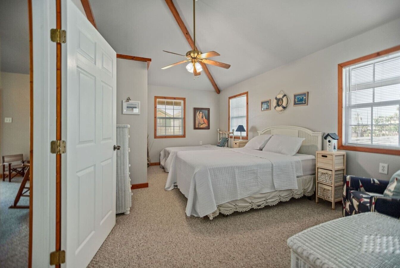 Une chambre à coucher avec un lit, un ventilateur de plafond, un radiateur et une fenêtre.