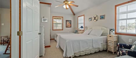 Une chambre à coucher avec un lit, un ventilateur de plafond, un radiateur et une fenêtre.