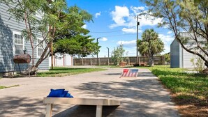 Ein Garten mit einem Betonweg, einem kleinen Tisch und einer Flagge.