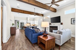 A modern living room with a fireplace, a television, and a ceiling fan. - Caron House - Bay St. Louis (Bay St. Louis)