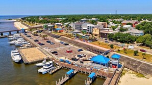 A marina with boats docked, a train station, and a bridge in the background. - Caron House - Bay St. Louis (Bay St. Louis)