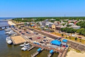 Uma marina com barcos atracados, uma estação de trem e uma ponte ao fundo.
