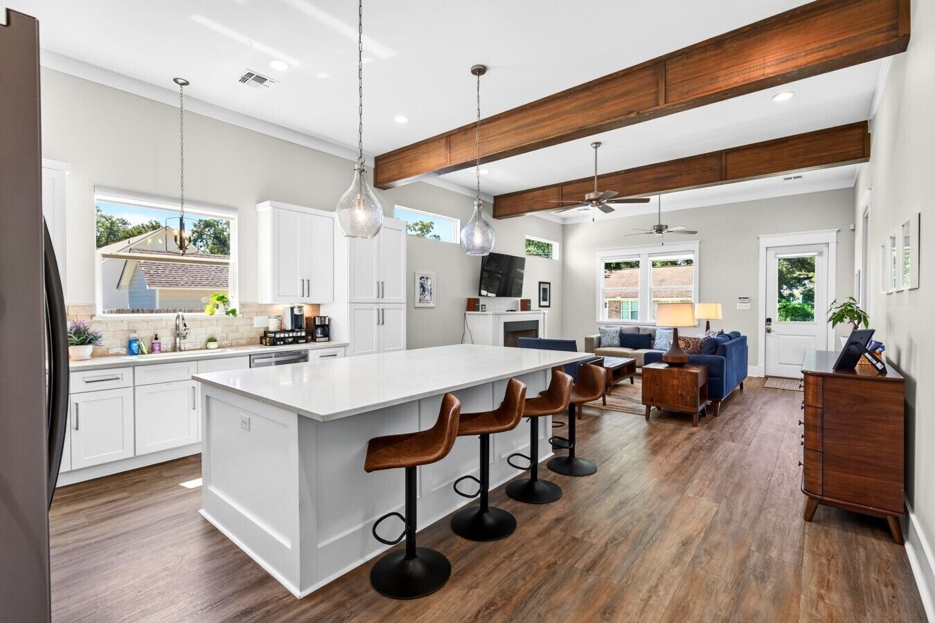 Una cocina moderna con una isla grande, taburetes de bar y una zona de comedor con sofá y mesa de centro.
