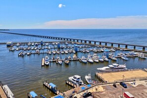 Ein Yachthafen mit zahlreichen vertäuten Booten, eine Pier, die ins Wasser ragt, und ein klarer Himmel.