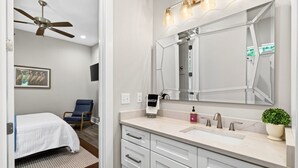 A modern bathroom with a large mirror, vanity, and a ceiling fan. - Caron House - Bay St. Louis (Bay St. Louis)