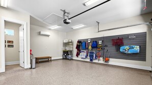 A spacious room with a bench, a projector, and various sports equipment on the wall. - Caron House - Bay St. Louis (Bay St. Louis)