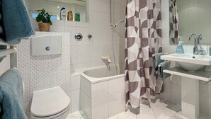 Ein modernes Badezimmer mit Toilette, Badewanne, Dusche und Waschbecken.