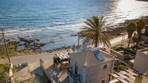 A stone building with a balcony, a palm tree, and a view of the sea. - Pleades Seaside Taygeta Gem in Mani, Near the Sea (Agios Nikolaos)