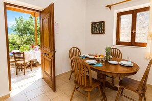A dining area with a wooden table set for four, surrounded by chairs. - Pleades Seaside Taygeta Gem in Mani, Near the Sea (Agios Nikolaos)