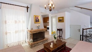 A living room with a fireplace, a chandelier, and a dining area. - Pleades Seaside Taygeta Gem in Mani, Near the Sea (Agios Nikolaos)