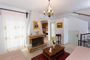 A living room with a fireplace, a chandelier, and a dining area. - Pleades Seaside Taygeta Gem in Mani, Near the Sea (Agios Nikolaos)