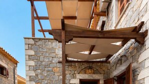 A stone-built outdoor seating area with a table and chairs, a stone archway, and a wooden pergola. - Pleades Seaside Taygeta Gem in Mani, Near the Sea (Agios Nikolaos)