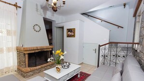 A living room with a fireplace, a sofa, a coffee table, and a staircase. - Pleades Seaside Asterope Gem in Mani, Near the Sea (Agios Nikolaos)