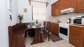 A kitchen with wooden cabinets, a dining table with chairs, a stove, and a microwave. - Pleades Seaside Asterope Gem in Mani, Near the Sea (Agios Nikolaos)