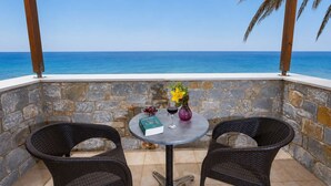 A stone-walled outdoor seating area with two wicker chairs and a small round table, overlooking a clear blue sea. - Pleades Seaside Asterope Gem in Mani, Near the Sea (Agios Nikolaos)