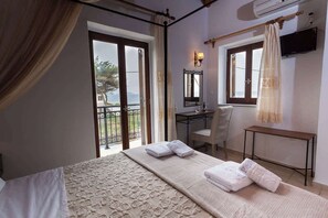 Une chambre d’hôtel avec un lit, un bureau, une chaise, une télévision et un balcon avec vue.