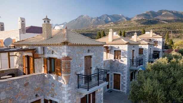 A traditional stone building with a courtyard, wooden shutters, and a view of mountains. - Pleades Seaside Asterope Gem in Mani, Near the Sea (Agios Nikolaos)