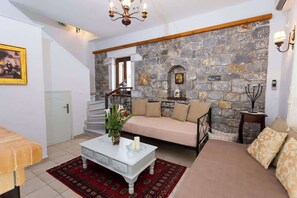Ein Wohnzimmer mit Steinwand, einer Couch, einem Couchtisch und einer Treppe.