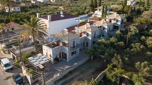 A residential area with stone buildings, a palm tree, and a hilly landscape in the background. - Pleades Seaside Alcyone Gem in Mani, Near the Sea (Agios Nikolaos)