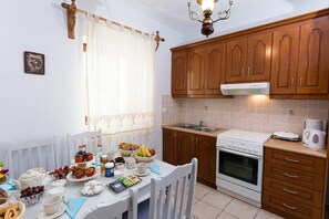 A kitchen with wooden cabinets, a white stove, and a sink. - Pleades Seaside Alcyone Gem in Mani, Near the Sea (Agios Nikolaos)