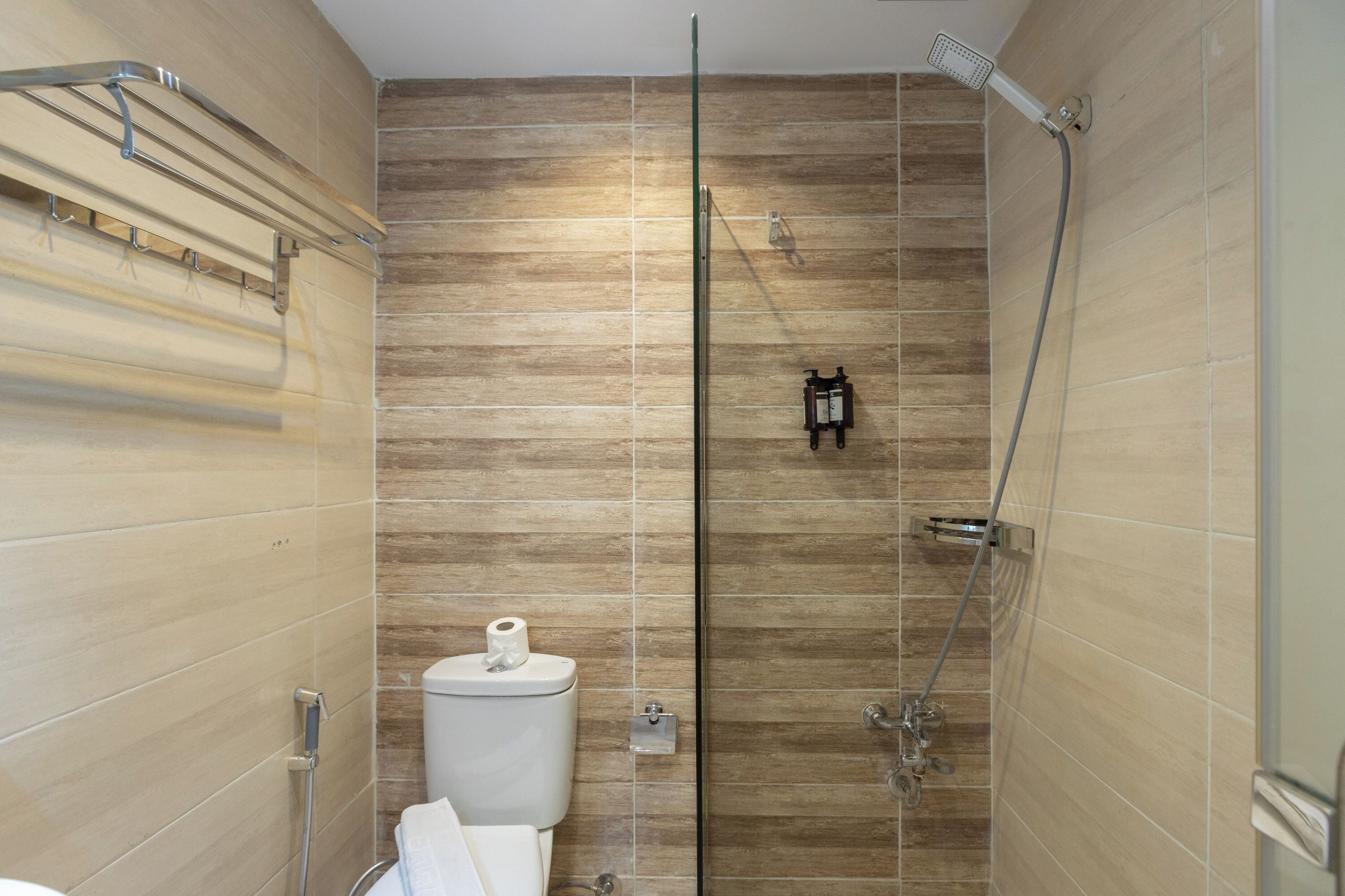 A bathroom with a shower, toilet, and towel rack.