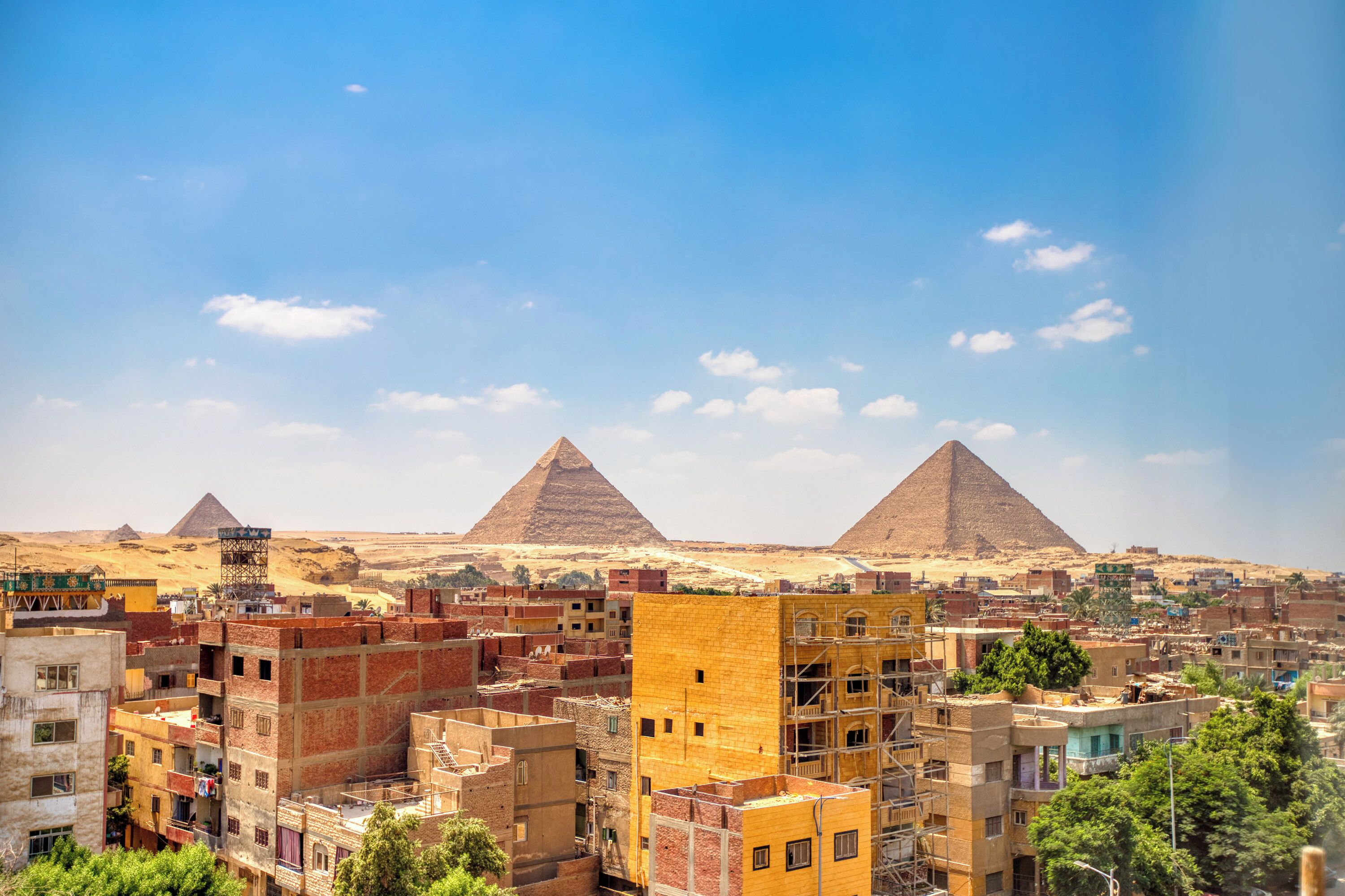 Paisagem urbana com várias pirâmides ao fundo e edifícios densamente agrupados em primeiro plano.