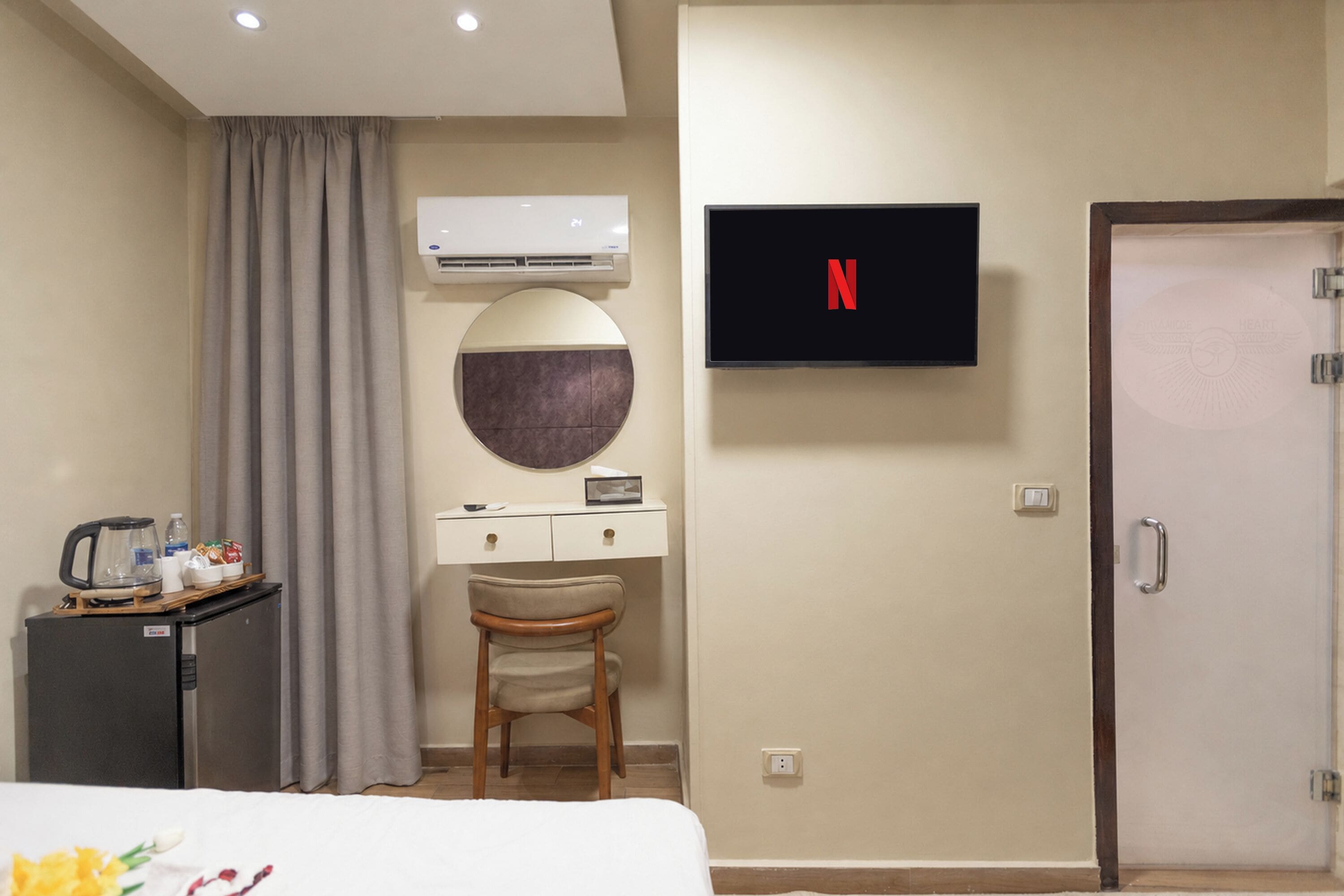 Une chambre d’hôtel comprenant un lit, un bureau avec une chaise, un téléviseur fixé au mur et un appareil de climatisation.