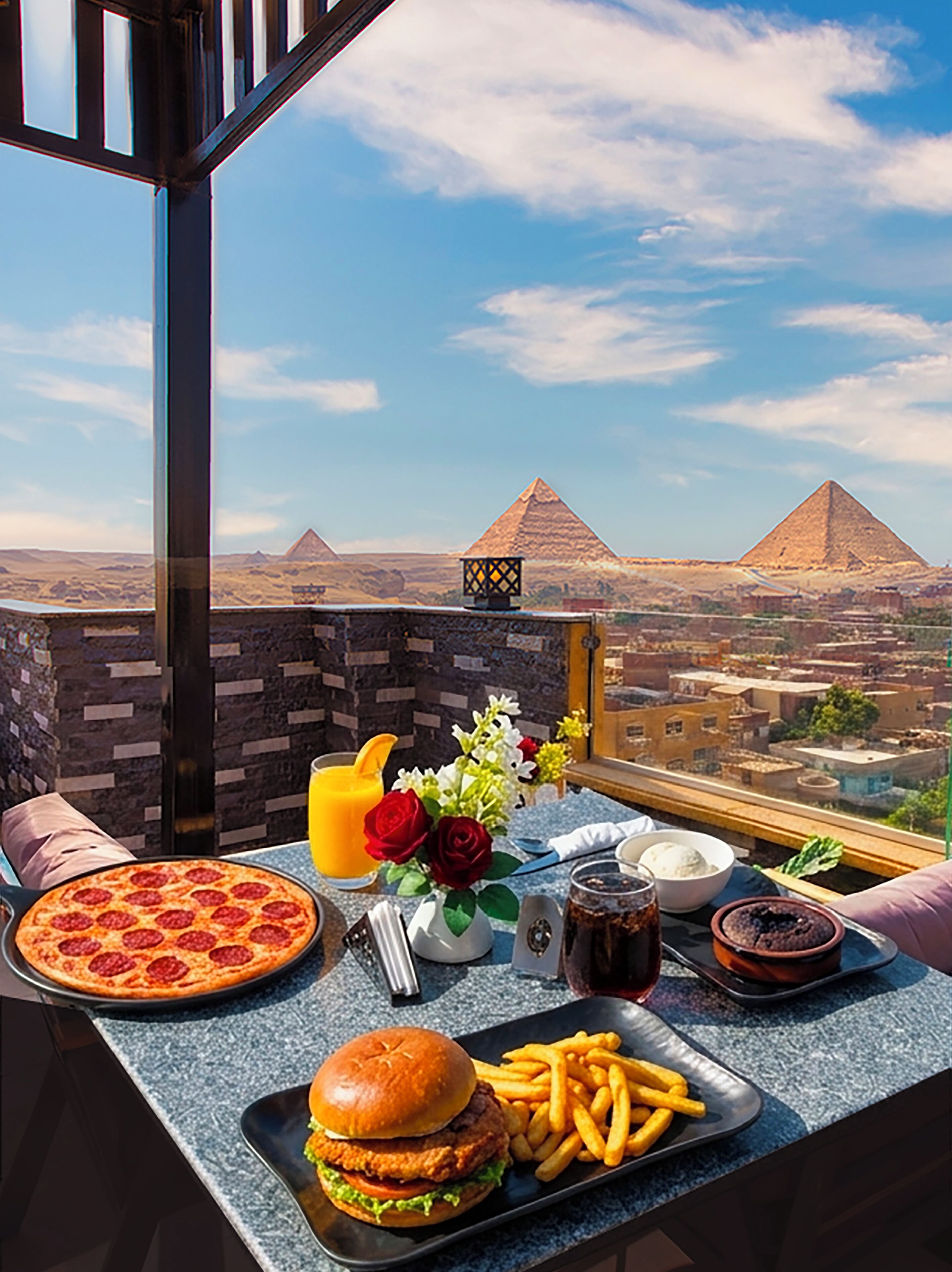 A dining table with food and drinks, a view of pyramids, and a stone wall.