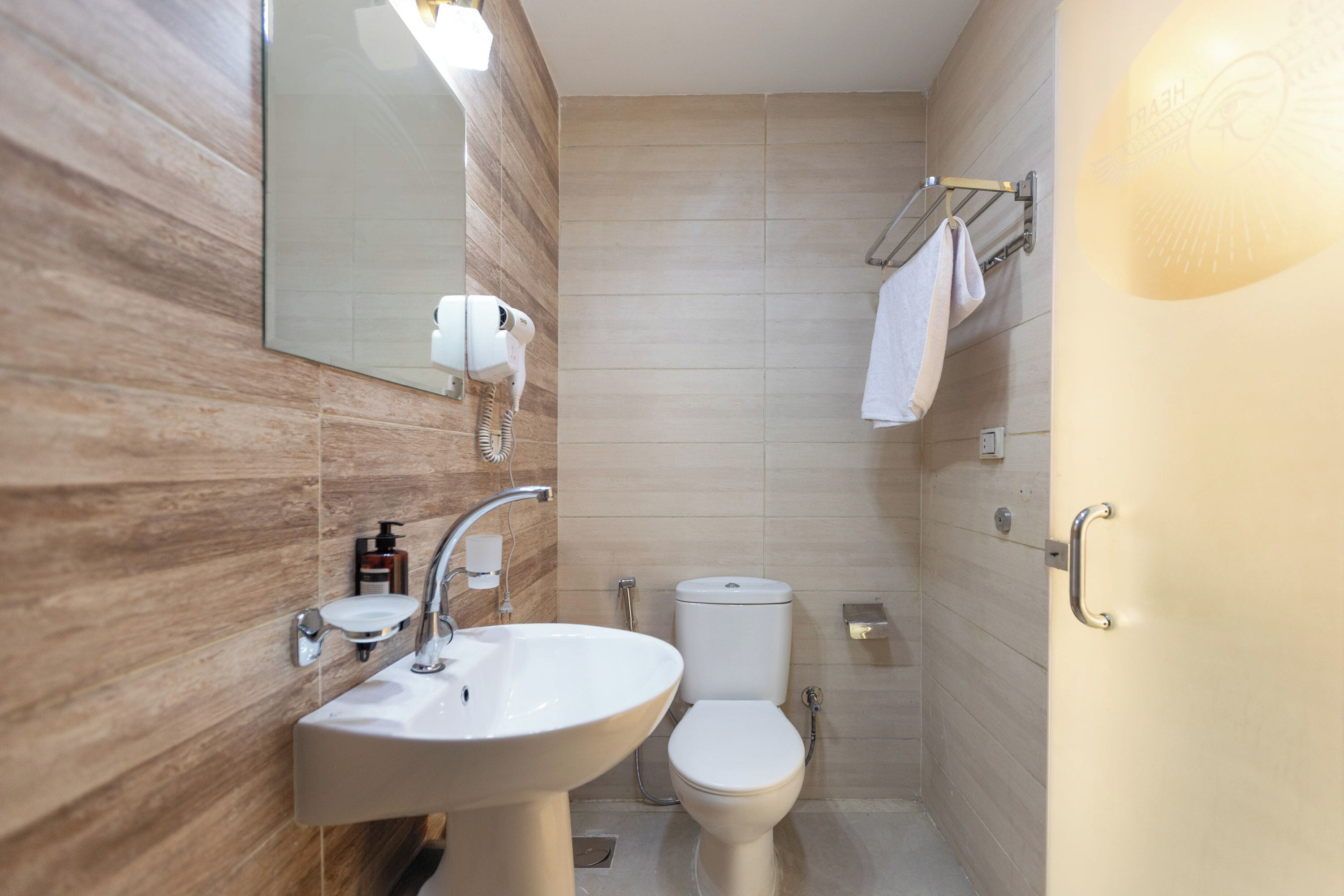 A bathroom with a sink, mirror, toilet, and towel rack.