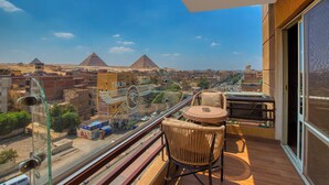 Un balcón con vistas a pirámides, un paisaje urbano y una barandilla de vidrio.