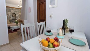 Een eethoek met een tafel gedekt voor twee personen, met een fruitmand, twee wijnglazen en een kaars.