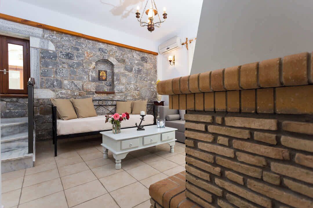 Una sala de estar con pared de piedra, chimenea, sofá, mesa de centro y escalera.