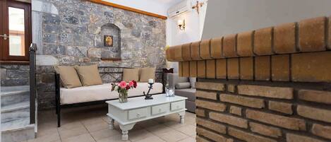 Una sala de estar con pared de piedra, chimenea, sofá, mesa de centro y escalera.