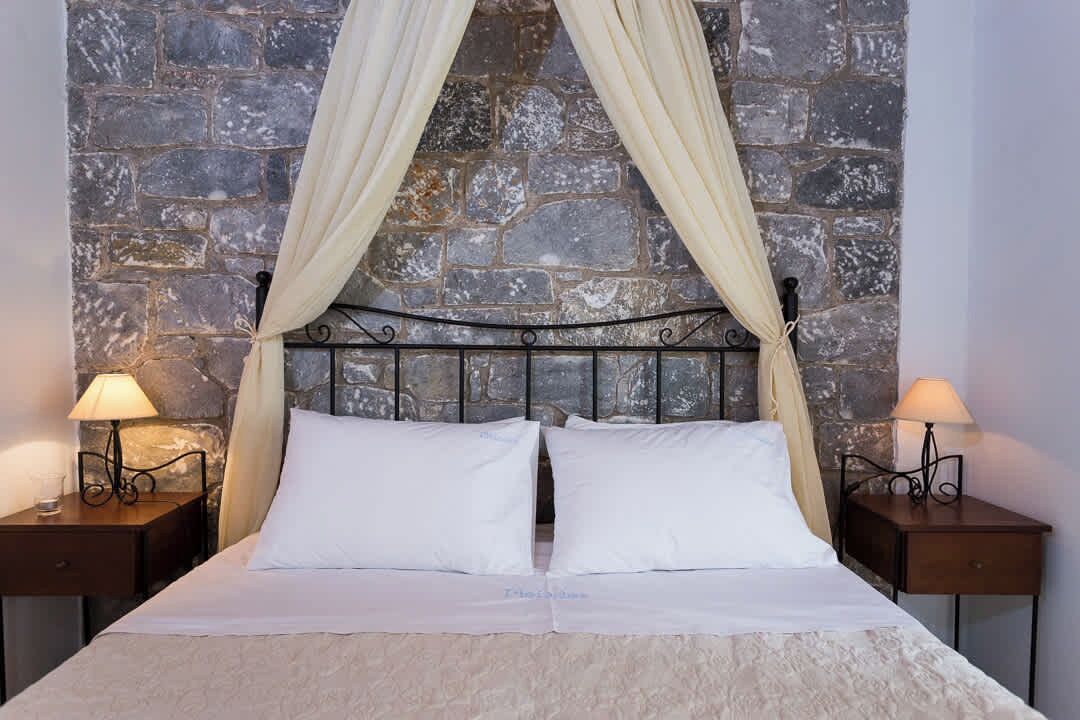 A bed with a stone wall backdrop, two bedside lamps, and a canopy.