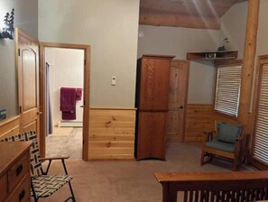 Una habitación con muebles de madera, una silla, una mesa y una puerta que da a otra estancia.