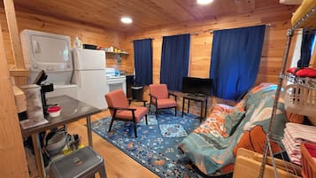 A cozy cabin interior with a kitchenette, a TV, a sofa, and a dining area.