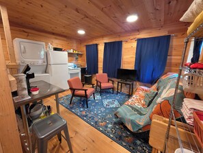 A cozy cabin interior with a kitchenette, a TV, a sofa, and a dining area.