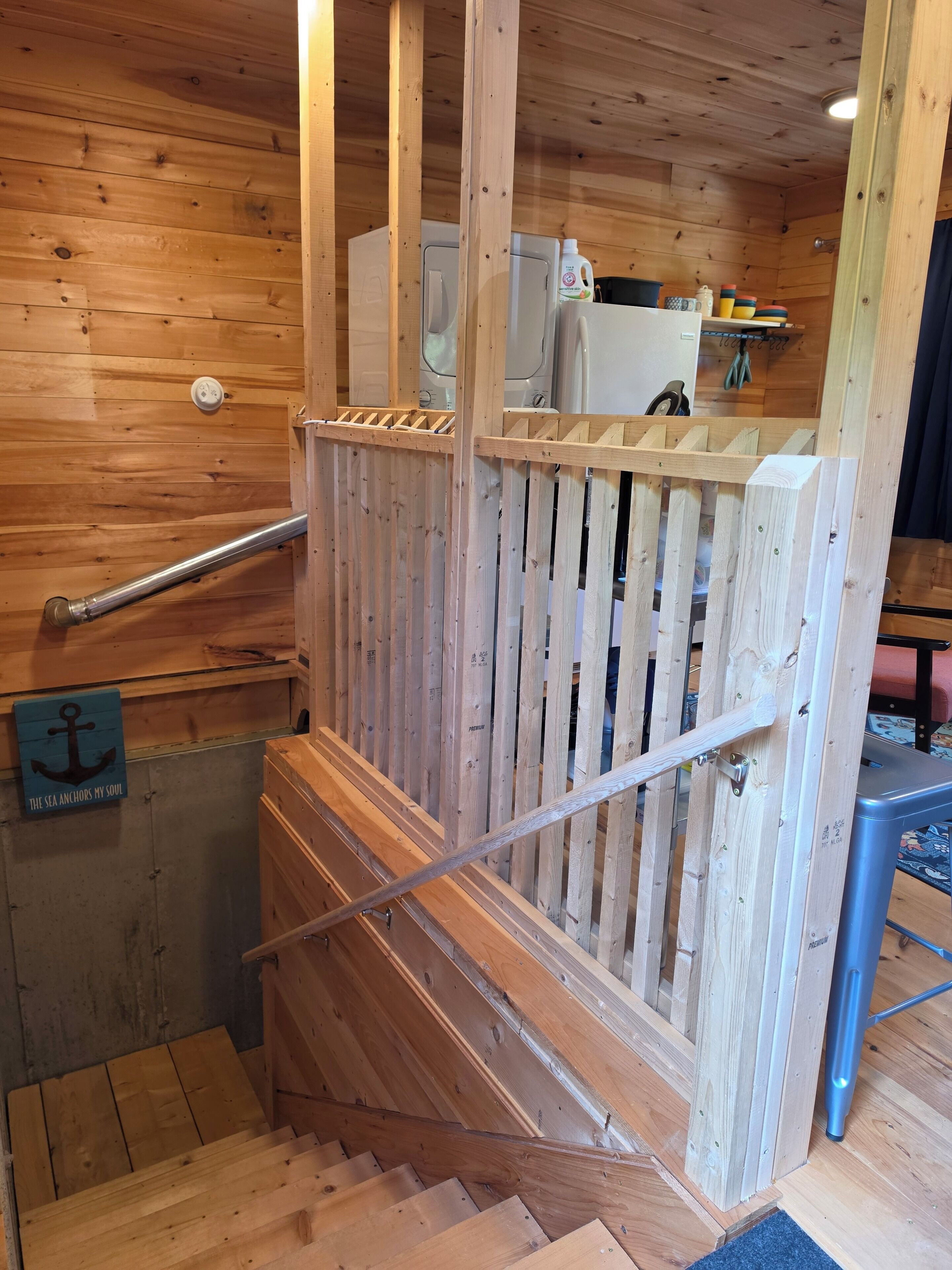 A wooden staircase with a handrail, a wooden fence, and a sign that reads 'The sea anchors my soul.'
